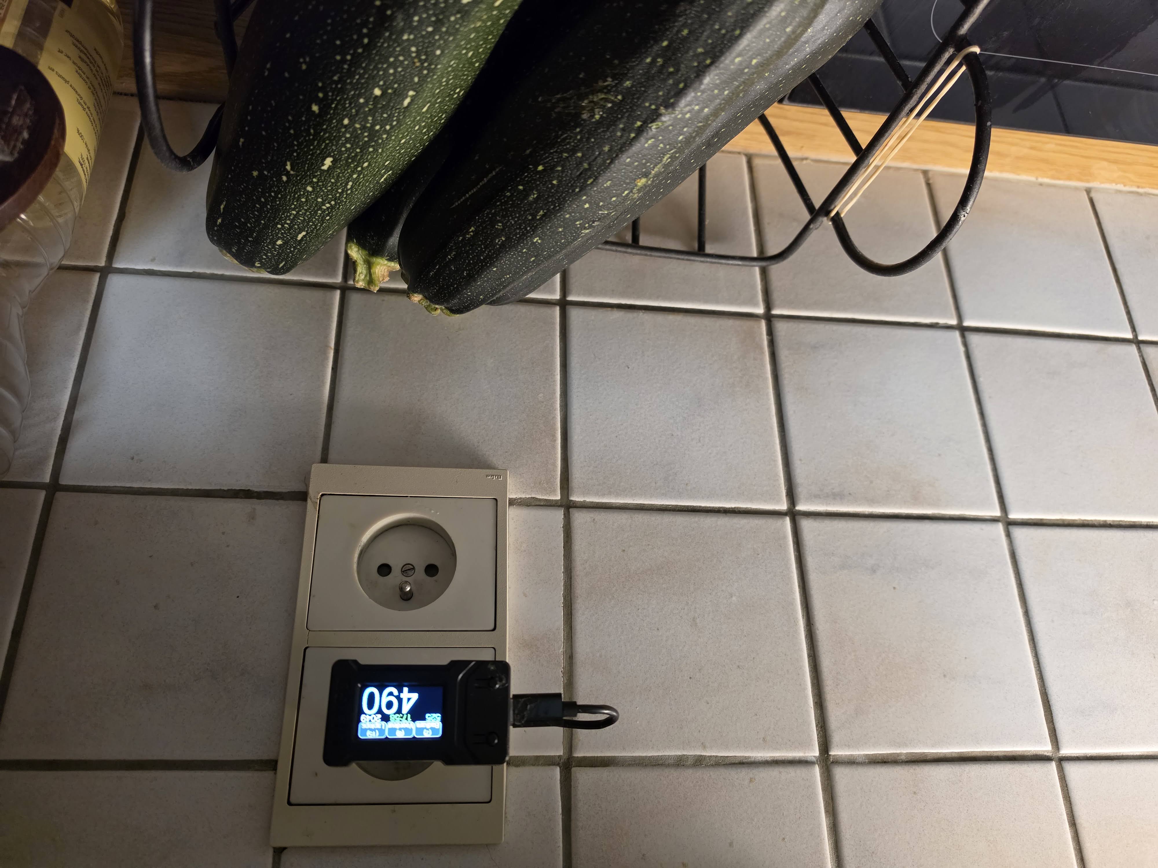 Lilygo T-Display aan de muur naast een stopcontact in de keuken